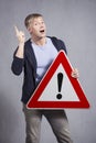 Man holding warning road sign with exclamation mark.