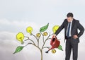 Man holding watering can and Drawing of Money and idea graphics on plant branches on wall