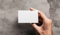 Man holding white business card on concrete wall background Royalty Free Stock Photo
