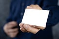 Man holding white business card on concrete wall background, adult man hand holding empty business card in front of camera Royalty Free Stock Photo