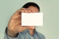 Man holding white business card on concrete wall background, businessman closes his eyes business card. Blank for text. White busi Royalty Free Stock Photo