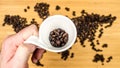 Man is holding white ceramic cup full of coffee beans Royalty Free Stock Photo