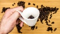 Man is holding white ceramic cup full of coffee beans Royalty Free Stock Photo