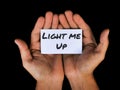Man holding white paper in palm with text LIGHT ME UP.
