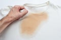 A man is holding a white t-shirt with a spilled tea stain. Sloppiness concept. Top view.