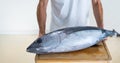 Man holding a whole tuna on wooden board. Fresh fish