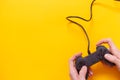 Man holding wired gamepad or video game controller on yellow background. Top view, flat lay Royalty Free Stock Photo