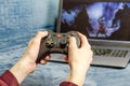 man holding wireless game controller connected to laptop. Gamepad in hands on background of laptop Royalty Free Stock Photo