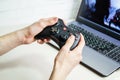 man holding wireless game controller connected to laptop. Gamepad in hands on background of laptop Royalty Free Stock Photo