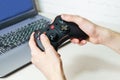 man holding wireless game controller connected to laptop. Gamepad in hands on background of laptop Royalty Free Stock Photo