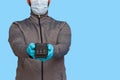 A man holding a wireless POS terminal to pay by credit card. In rubber gloves and face mask. Isolated on blue background Royalty Free Stock Photo