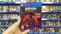 Man holding Wolfenstein Youngblood Deluxe Edition videogame on Sony Playstation 4 console in store