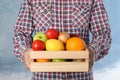 Man holding wooden crate filled with fresh vegetables and fruits against color background Royalty Free Stock Photo