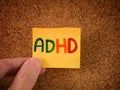 A man holding a yellow paper note with the abbreviation ADHD on it