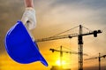 Man holding the yellow safety helmet at construction site with crane background silhouette Royalty Free Stock Photo