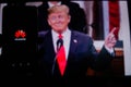 A man holds an android-smartphone that shows the logo for the google play store in front of the picture of Donald Trump