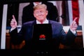 A man holds an android-smartphone that shows the logo for the google play store in front of the picture of Donald Trump