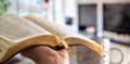 A man holds a Bible against the background of the living room. Reading a book in a cozy atmosphere Royalty Free Stock Photo