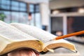 A man holds a Bible with a pencil, against the background of the living room. Reading a book in a cozy atmosphere Royalty Free Stock Photo