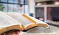 A man holds a Bible with a pencil, against the background of the living room. Reading a book in a cozy atmosphere Royalty Free Stock Photo