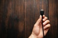 A man holds black HDMI cable in his hands on a dark wooden background. Different interfaces connecting devices