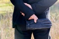 Man holds black leather gloves, from the back