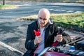 The man holds a black and red battery cable and tries to connect the cable to his car.