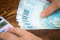 Man holds Brazilian money, rais, and counts on expenses or earnings calculator, Financial concept, home budgets in Brazil