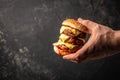 man holds burger juicy burger with triple patty with hands. banner, menu, recipe place for text