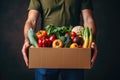 a man holds a cardboard box with groceries in his hands. Food service and delivery concept. Copy space mockup Royalty Free Stock Photo