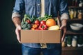 a man holds a cardboard box with groceries in his hands. Food service and delivery concept. Copy space mockup Royalty Free Stock Photo