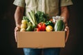 a man holds a cardboard box with groceries in his hands. Food service and delivery concept. Copy space mockup Royalty Free Stock Photo