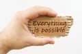 A man holds a cardboard in his hand on which it is written - Everything is possible