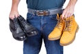 Man holds classic winter boots and fashionable brown nubuck boots in his hands. Difficult choice