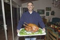 Man holds cooked turkey in front of a table set for Thanksgiving dinner in Ojai, California