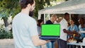 Man holds device with green screen
