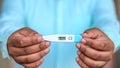 Man holds digital thermometer with temperature reading in Fahrenheit closeup