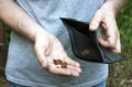 A man holds an empty purse and small coins in his hands. The concept of economic and financial crisis, poverty