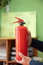 man holds a fire extinguisher in his hands against the background of a fire evacuation plan. Royalty Free Stock Photo