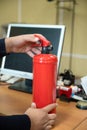 man holds a fire extinguisher in his hands against the background of office equipment. Royalty Free Stock Photo