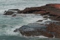 Man holds fishing rod to catch fish amid wild waves in Legzira Beach. Person stands on sandstone rock formation. Rugged landscape. Royalty Free Stock Photo