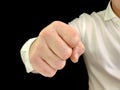 A man holds a fist in front of him. A man in a white shirt shows a hand gesture, on a black background. Concept: aggression, anger Royalty Free Stock Photo
