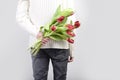 a man holds flowers behind his back. Tulips in the hands of a young man. Flower greetings for women. Male hands with a bouquet of Royalty Free Stock Photo