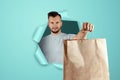 A man holds food in packages in his hands, punching a blue paper background. Fast delivery concept, ready food, modern world