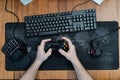 a man holds a game pad around a gaming keyboard in his hands, a game pad mouse. top view Royalty Free Stock Photo