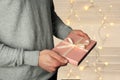 Man holds a gift in his hand in a pink box with a satin ribbon on a light background, holiday concept Royalty Free Stock Photo