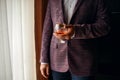 Man holds a glass with whiskey, dressed in a classic jacket, handsome man Royalty Free Stock Photo