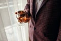Man holds a glass with whiskey, dressed in a classic jacket, handsome man Royalty Free Stock Photo