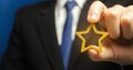 Man holds a golden star in his hand. Symbol of success and excellence. Good reputation, prestige, high recognition. Status, rating