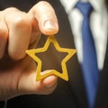 Man holds a golden star in his hand. Symbol of success and excellence. Good reputation, prestige, high recognition. Status, rating